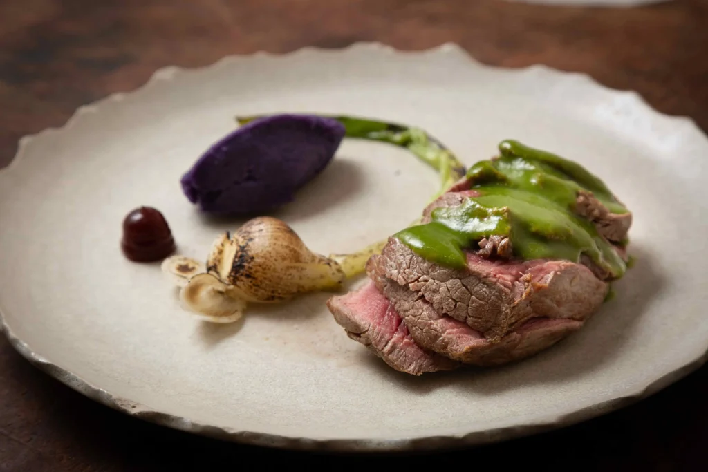 Beef fillet with green sauce, purple potatoes and spring onion